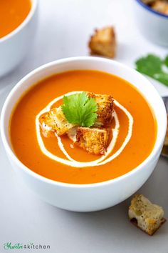 a white bowl filled with carrot soup and garnished with parsley