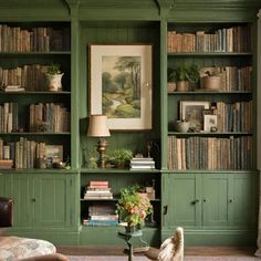 a living room filled with lots of green bookshelves