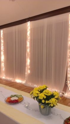 the table is set up with flowers and plates of food on it, along with white drapes