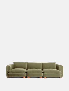 an olive green couch with wooden legs on a white background, it's all lined up and ready to be used as a sofa