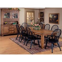 a dining room table with black chairs and a rug on the floor in front of it