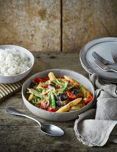 a bowl filled with pasta and vegetables next to two bowls full of rice on a wooden table