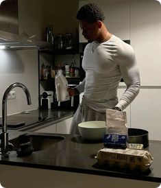 a man standing in a kitchen next to a counter with a bowl and bag on it