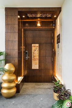 the entrance to an apartment building with large gold balls on the floor and planters in front