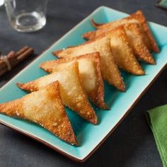 some food is sitting on a blue plate with cinnamon sticks next to it and wine glasses