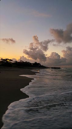 the sun is setting over the ocean with clouds in the sky and water on the beach