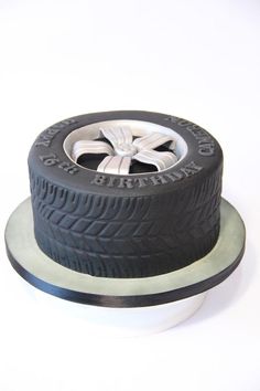 a car tire sitting on top of a white plate next to a black and silver wheel