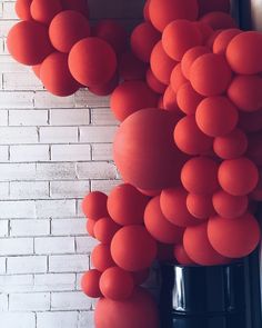 red balloons are hanging from the side of a brick wall