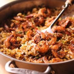 a pan filled with rice and shrimp on top of a table