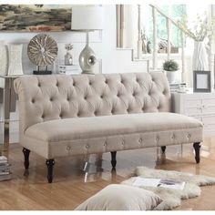 a gray tufted bench with books and a teapot on it in a white room