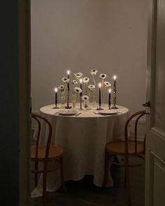 a white table topped with lots of candles and flowers on top of a round table