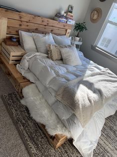 a bed made out of wooden pallets with pillows and blankets on top of it