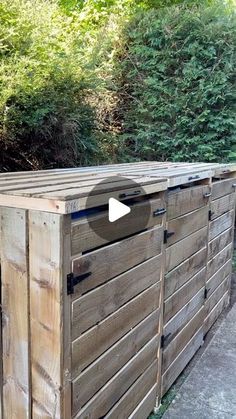 a large wooden box sitting in the middle of a park next to some bushes and trees