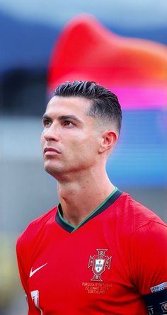 a man with a soccer jersey on standing in front of a red and blue flag