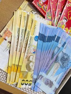 several different bank notes sitting on top of each other next to a pile of red packets