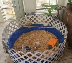 a large blue and white basket filled with lots of stuff next to a window in a house