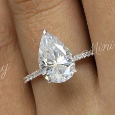 a woman's engagement ring with a pear shaped diamond in the center and pave band