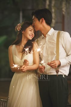 a man and woman standing next to each other with sparklers in their hands,