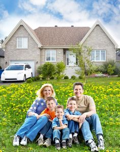 a family sitting on the grass in front of their house