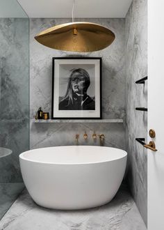 a white bath tub sitting next to a bathroom sink under a golden light hanging above it