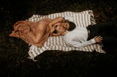 a man and woman laying on a blanket in the grass