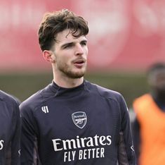 two soccer players standing next to each other on a field with one looking at the camera