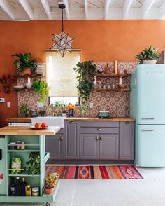 a kitchen with an orange wall and blue refrigerator freezer next to a green island