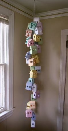 colorful paper houses hanging from the ceiling in front of a window