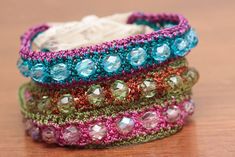 three crocheted bracelets sitting on top of a wooden table