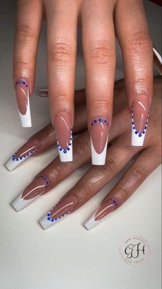 a woman's hands with white and blue nail polishes on their nails,