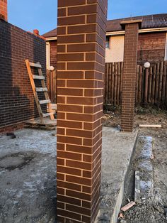 a fire hydrant sitting next to a tall brick pillar in the middle of a yard