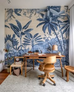 a room with a desk, chair and wallpaper that has palm trees on it