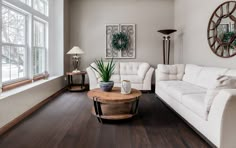 a living room with white furniture and wood floors