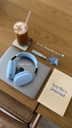 there is a book and headphones on the table next to an iced drink with a straw in it