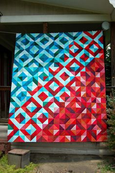 a colorful wall hanging on the side of a house with red, blue and green triangles