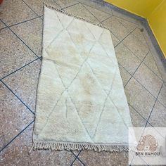 a white rug sitting on top of a tile floor next to a yellow wall and tiled floor