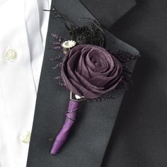 a purple boutonniere on a black suit lapel