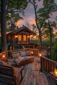 a wooden deck with two couches and some lights on the side of it at dusk