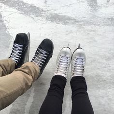 two people wearing black and white sneakers sitting on ice