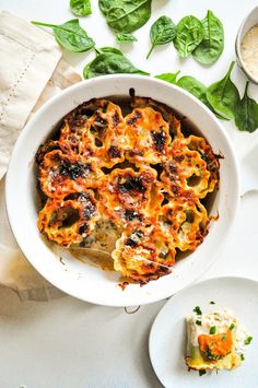 a casserole dish with spinach, cheese and sauce in it on a white table