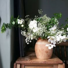 a vase filled with white flowers sitting on top of a wooden table