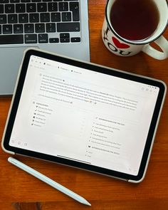 a tablet computer sitting on top of a wooden desk next to a cup of coffee