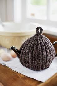 a knitted tea pot sitting on top of a wooden tray next to an egg