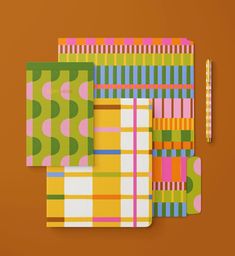 three notebooks with different patterns on them and a pencil next to one that is empty