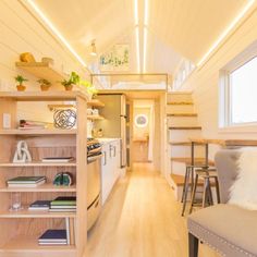 the interior of a tiny house with wood flooring and white walls, along with open shelving