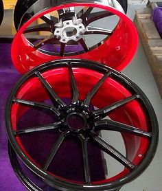 two red wheels are on display in a showroom with purple carpet and other items