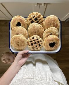 a person holding up a plate with several pastries on it in front of them