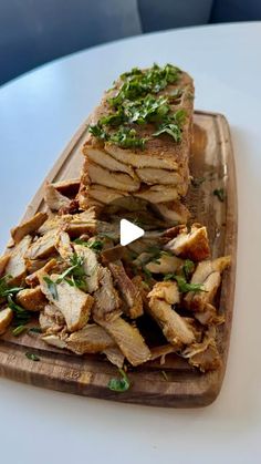 a wooden cutting board topped with slices of meat and garnished with parsley