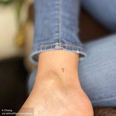 a woman's foot with a tiny cross tattoo on the left side of her ankle