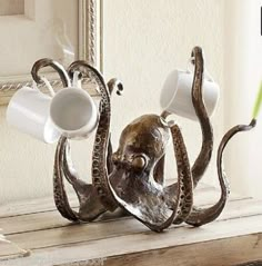 an octopus sculpture holding two cups on it's back legs, with a green toothbrush in its mouth